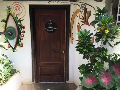 a wooden door with a sign on it next to plants at Pura Vida Hostel in Tamarindo