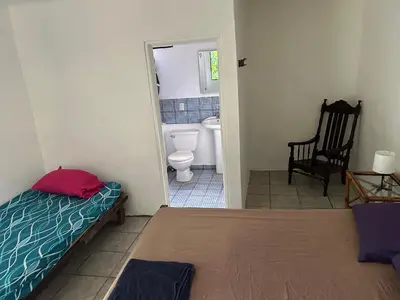 a bedroom with a bed and a bathroom with a toilet at Pura Vida Hostel in Tamarindo