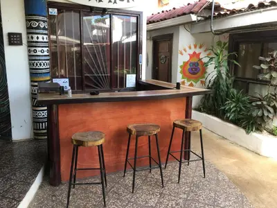 a bar with three stools in front of a building at Pura Vida Hostel in Tamarindo