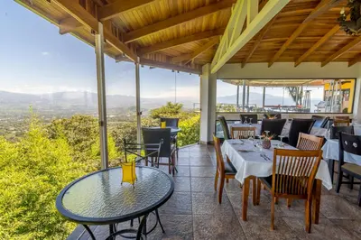 a patio with tables and chairs and a view at Barons Resort in Atenas