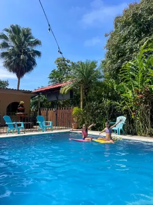 two children are playing in a swimming pool at Hospedaje Colibri in Manuel Antonio