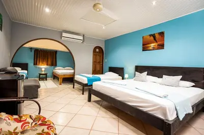 a bedroom with two beds and a blue wall at Hospedaje Colibri in Manuel Antonio
