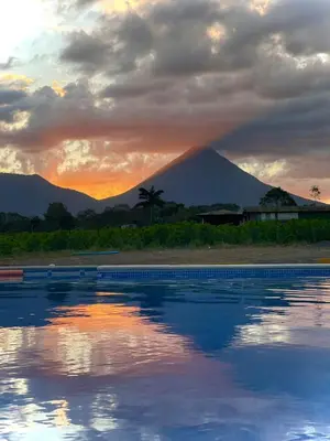 a sunset over a pool with a mountain in the background at Casa Stela in Fortuna
