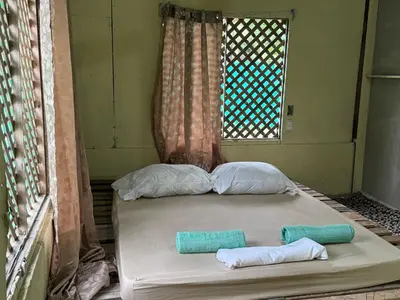 a bed in a room with two pillows and a window at Beach Guesthouse in Manuel Antonio