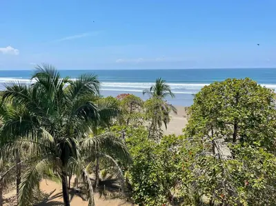 a beach with palm trees and the ocean at Bejuco Beachfront Condo FRENTE A LA PLAYA hermoso condominio NUEVO in Esterillos Este