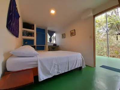 a bedroom with a white bed and a large window at Eco-Turismo Guayacanes in Sámara