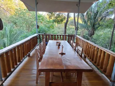 a long wooden table on a deck with trees at Eco-Turismo Guayacanes in Sámara