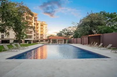 a swimming pool with chairs and a building at Tropical Luxury 2Bdr condo - Pool view - At the Beach in Tamarindo