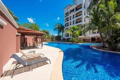 a swimming pool with two chairs and a building at Tropical Luxury 2Bdr condo - Pool view - At the Beach in Tamarindo