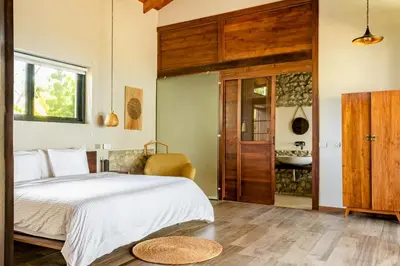a bedroom with a bed and a bathroom with a sink at THEA Resort & Retreats - Santa Teresa in Santa Teresa Beach