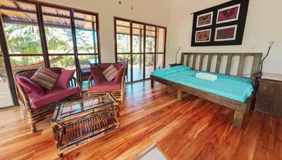a living room with a bed and two chairs at Jungle Cabin in Drake Bay in Drake