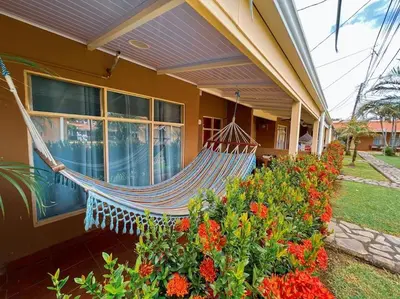 a hammock hanging from the side of a house with flowers at Villa Coco 55, Few Steps from beach and Free Wifi in Jacó