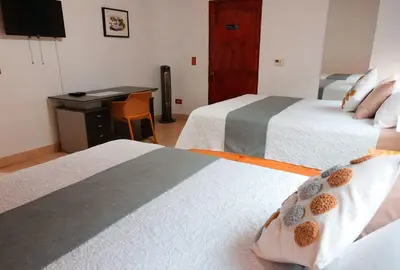 a hotel room with two beds and a desk at Trebol Amarillo Bed & Breakfast in Escazu