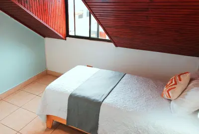 a bedroom with a white bed with a large window at Trebol Amarillo Bed & Breakfast in Escazu