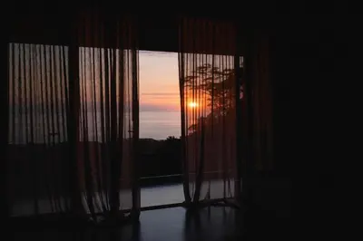 a room with a window with a view of the sunset at Aguamadera Ocean View Villas in Santa Teresa Beach