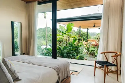 a bedroom with a bed and a large window at Aguamadera Ocean View Villas in Santa Teresa Beach