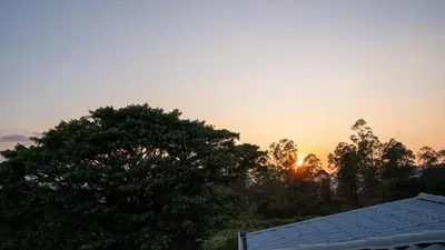 a sunset over a house with trees and a roof at Casa Familiar la Tortuga in Heredia