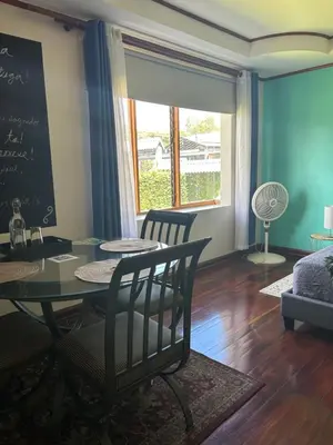 a dining room with a table and chairs and a chalkboard at Casa Familiar la Tortuga in Heredia