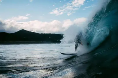 a person riding a wave on a surfboard in the ocean at Pura Vida Mini Hostel Santa Teresa in Santa Teresa Beach