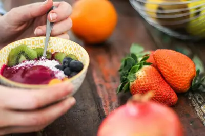 a person eating a bowl of fruit with a spoon at Pura Vida Mini Hostel Santa Teresa in Santa Teresa Beach