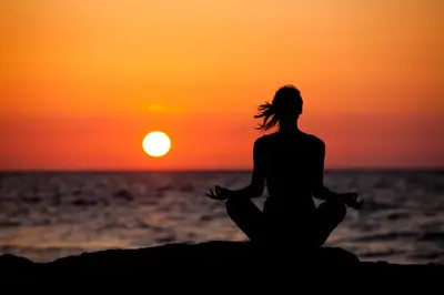 a woman sitting in meditation on the beach at sunset at Pura Vida Mini Hostel Santa Teresa in Santa Teresa Beach