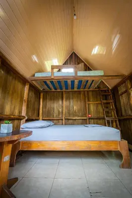 a bedroom with a bed in a wooden room at Pura Vida Mini Hostel Santa Teresa in Santa Teresa Beach