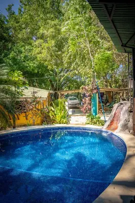 a large blue swimming pool with a slide at Pura Vida Mini Hostel Santa Teresa in Santa Teresa Beach