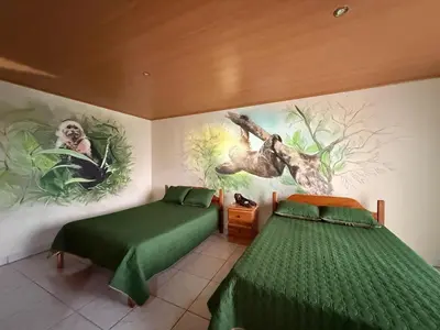 a bedroom with two beds and a painting on the wall at La Tigra Mountain House in San Gerardo