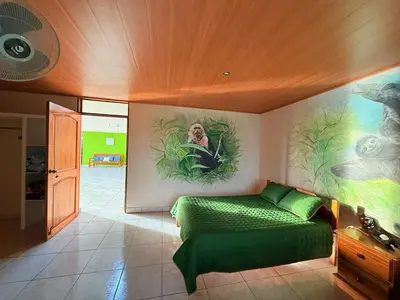 a bedroom with a green bed and a painting on the wall at La Tigra Mountain House in San Gerardo