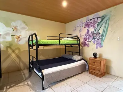 a bedroom with two bunk beds and a painting on the wall at La Tigra Mountain House in San Gerardo