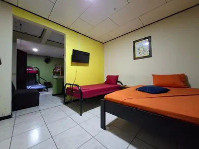 a bedroom with a bed and a couch and a tv at Hospedaje Doña koko in Puerto Limón