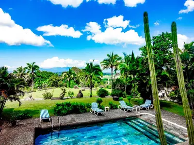 a resort pool with chairs and palm trees at Canal Grande Lodge in Piedades