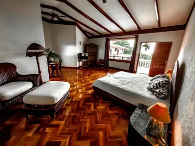 a bedroom with a bed and a chair in a room at Canal Grande Lodge in Piedades
