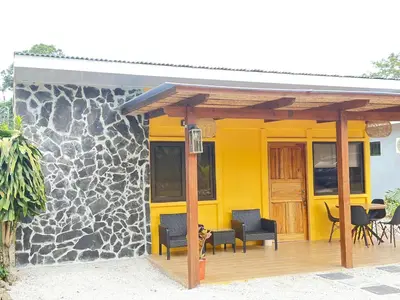 a yellow house with a deck with chairs and a dog at Casa CAXTUS in Brasilito