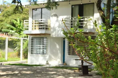 a white house with a porch and a balcony at Casa Buda Liberia Cerca del Aeropuerto in Liberia