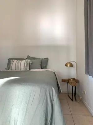 a white bedroom with a bed and a lamp at Casa Buda Liberia Cerca del Aeropuerto in Liberia