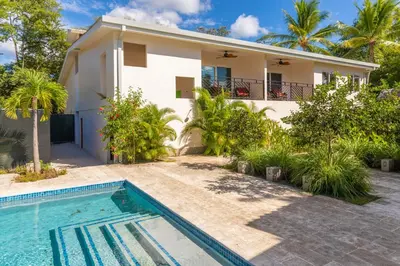 a villa with a swimming pool in front of a house at Palm Beach Inn in Playa Grande