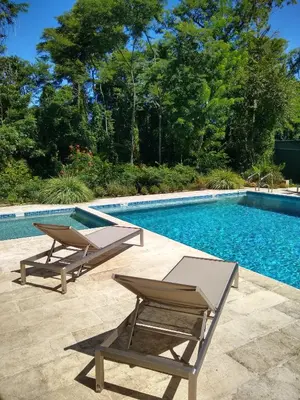 a swimming pool with two lounge chairs next to it at Palm Beach Inn in Playa Grande