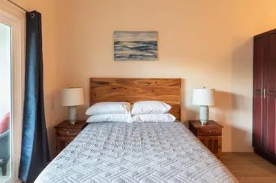 a bedroom with a bed with two pillows and two lamps at Palm Beach Inn in Playa Grande