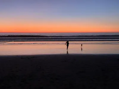 a person and a child standing on the beach at sunset at Palm Beach Inn in Playa Grande