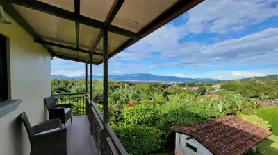 a balcony with two chairs and a view of the countryside at Coffee Garden Ranch Costa Rica in Concepción
