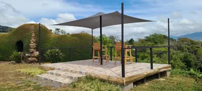 a table and chairs sitting on a platform with an umbrella at Coffee Garden Ranch Costa Rica in Concepción