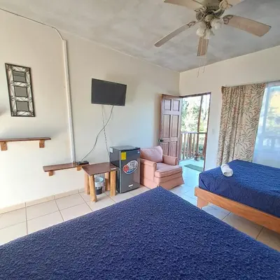 a bedroom with a blue bed and a tv at Georgi, Junquillal in Playa Junquillal