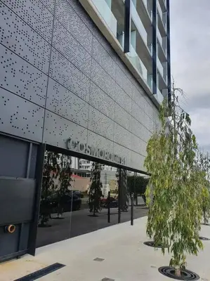 a glass building with trees in front of it at Cosmopolitan APT 1407, 5 Star Facilities, 15m SJO Airport, Parking, Pool, Gym in San José