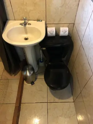 a bathroom with a black toilet and a sink at Pizote house in Monteverde Costa Rica