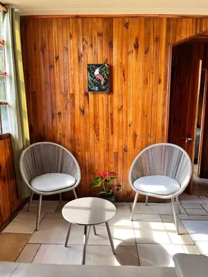 two chairs and a table in front of a wooden wall at Pizote house in Monteverde Costa Rica