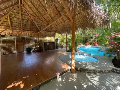 a patio with a straw umbrella and a swimming pool at Anam Apartments in Santa Teresa Beach