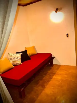 a red bench with pillows on it in a room at Anam Apartments in Santa Teresa Beach