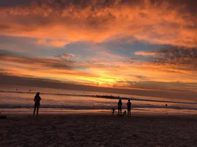 a group of people standing on the beach at sunset at Anam Apartments in Santa Teresa Beach