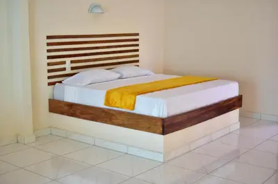 a bedroom with a bed with a wooden headboard at Tarcoles Birding Lodge in Tarcoles